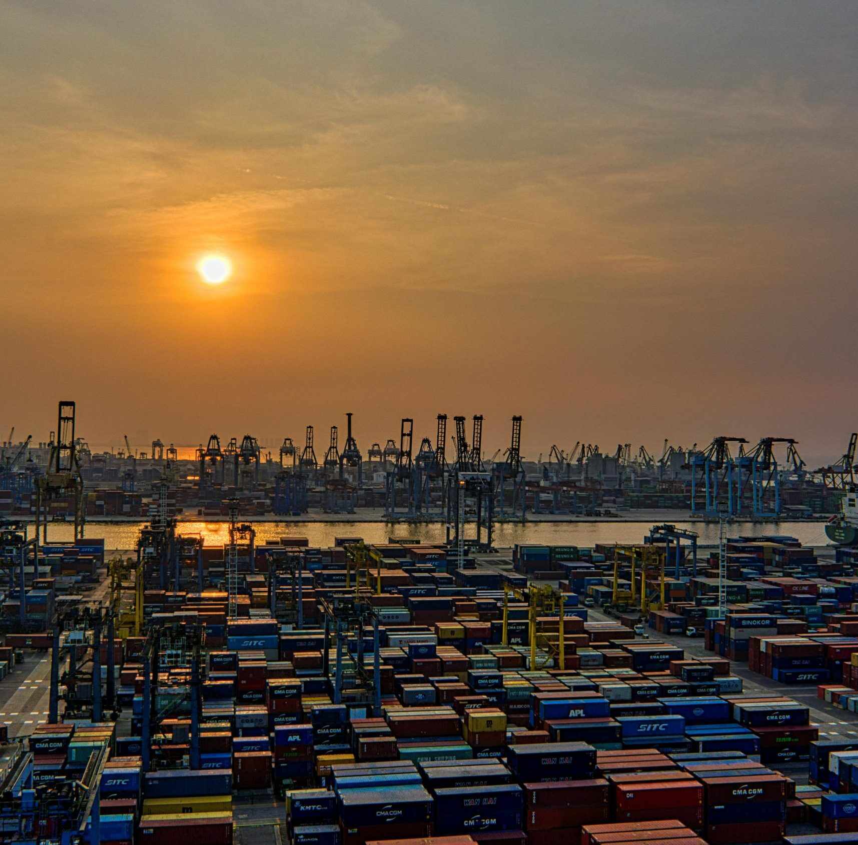 Shipping containers sitting at the port under the sunset